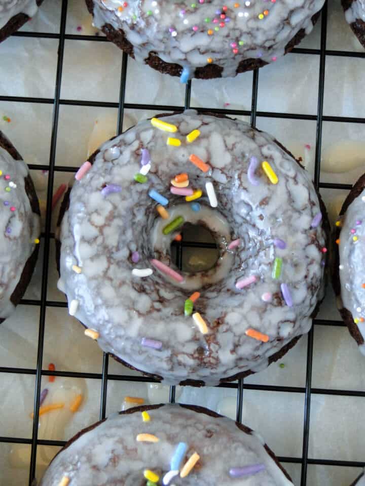 Close up top view of one glazed with sprinkles chocolate sour cream donut.