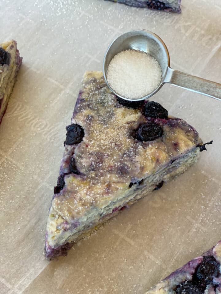 Sugar being sprinkled on a blueberry scone.