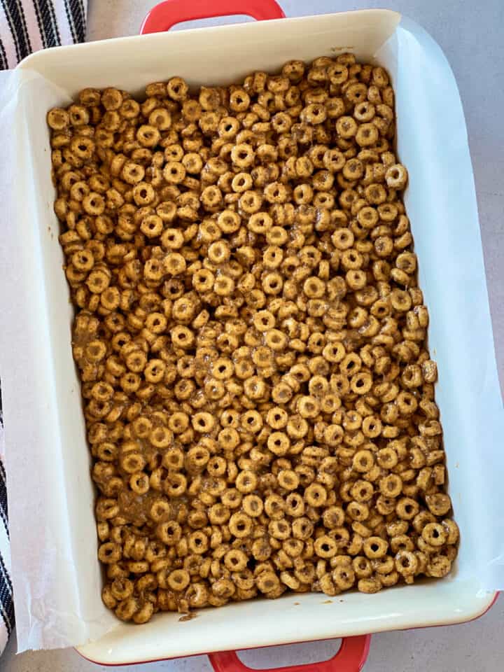 Peanut butter cheerio mixture pressed into 9x13 baking dish lined with parchment paper.