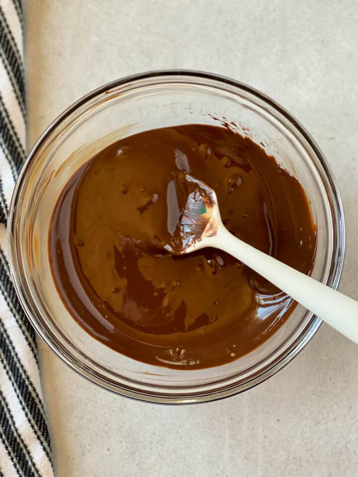 Melted chocolate in glass bowl with white spatula.