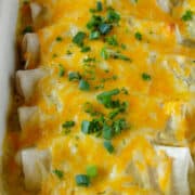 Close up side view of Salsa verde chicken enchiladas in baking dish.