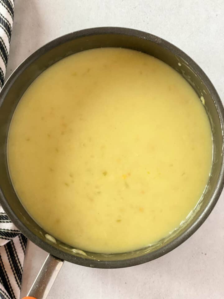 Chicken broth added to roux to make sauce in round sauce pan.