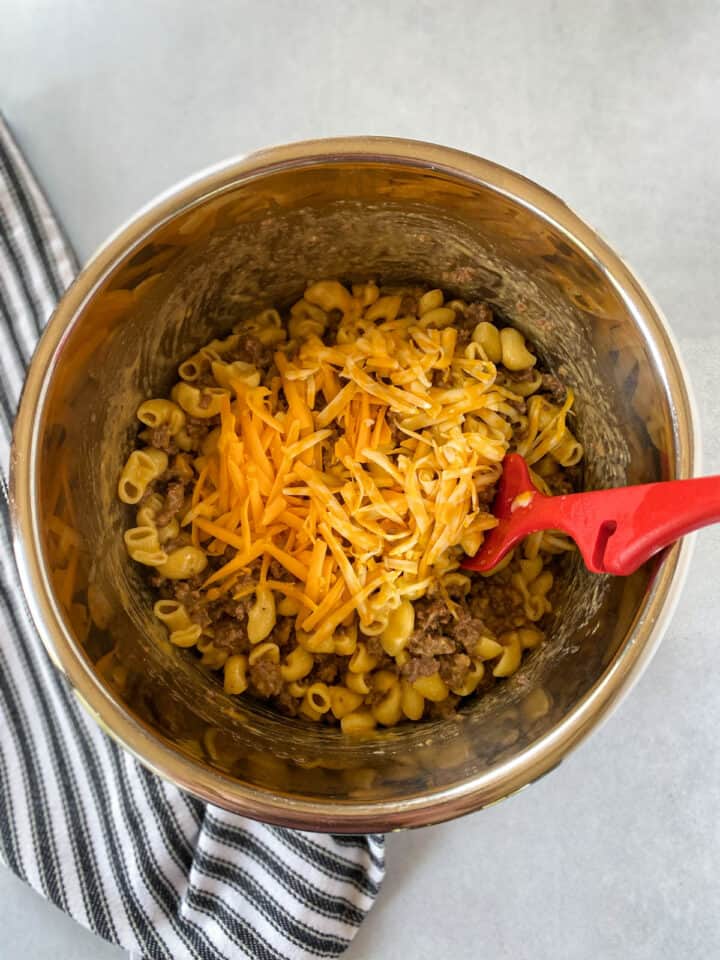 Shredded cheese added to cooked pasta and beef.