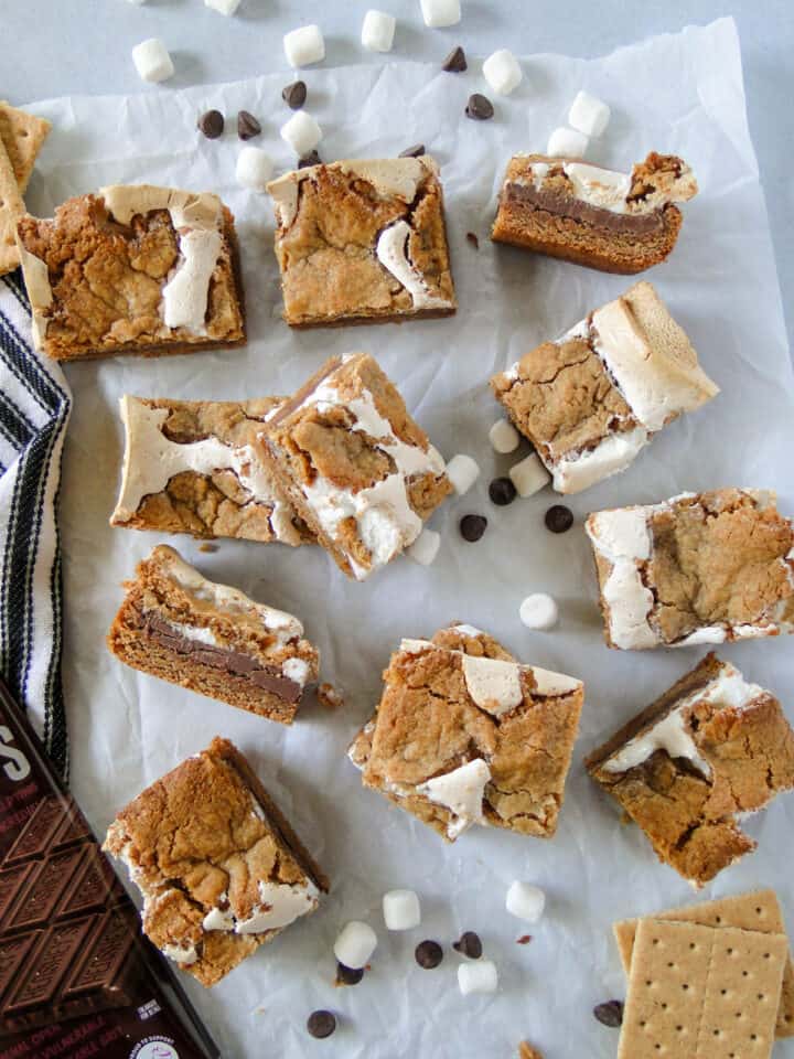 Top view of sliced s'mores bars with some bars stacked and some bars on their side with garnishes of marshmallows and chocolate.
