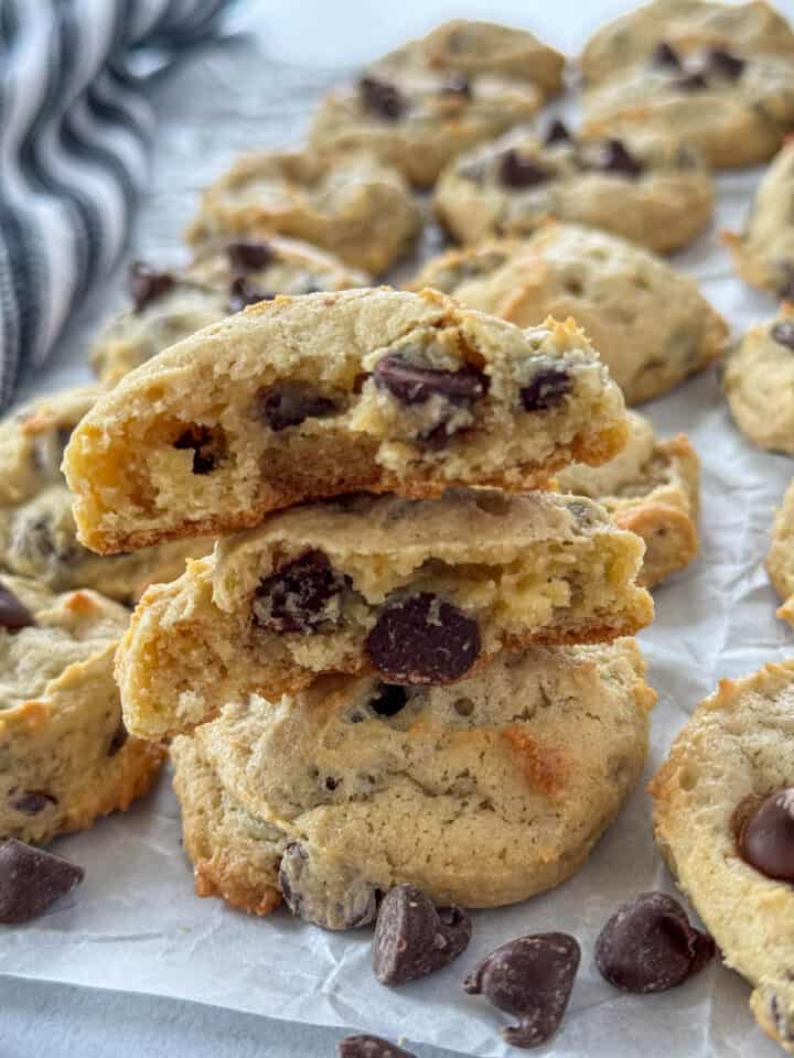 Cream cheese chocolate chip cookies stacked and top cookie broken in half showing center.