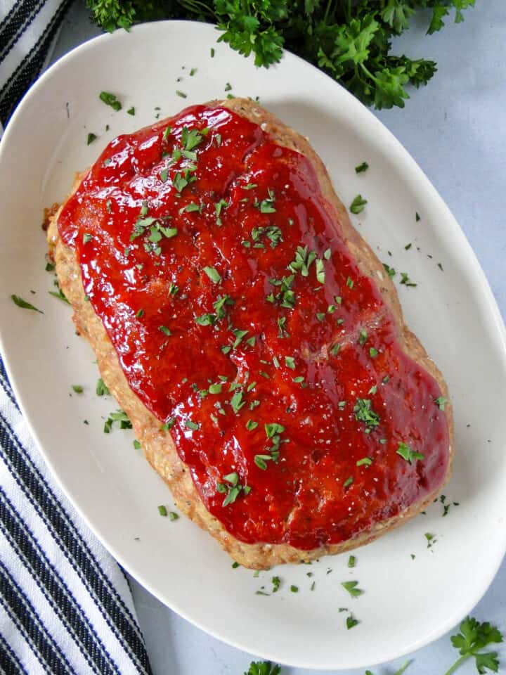 Top view of baked easy turkey meatloaf on white oval platter.
