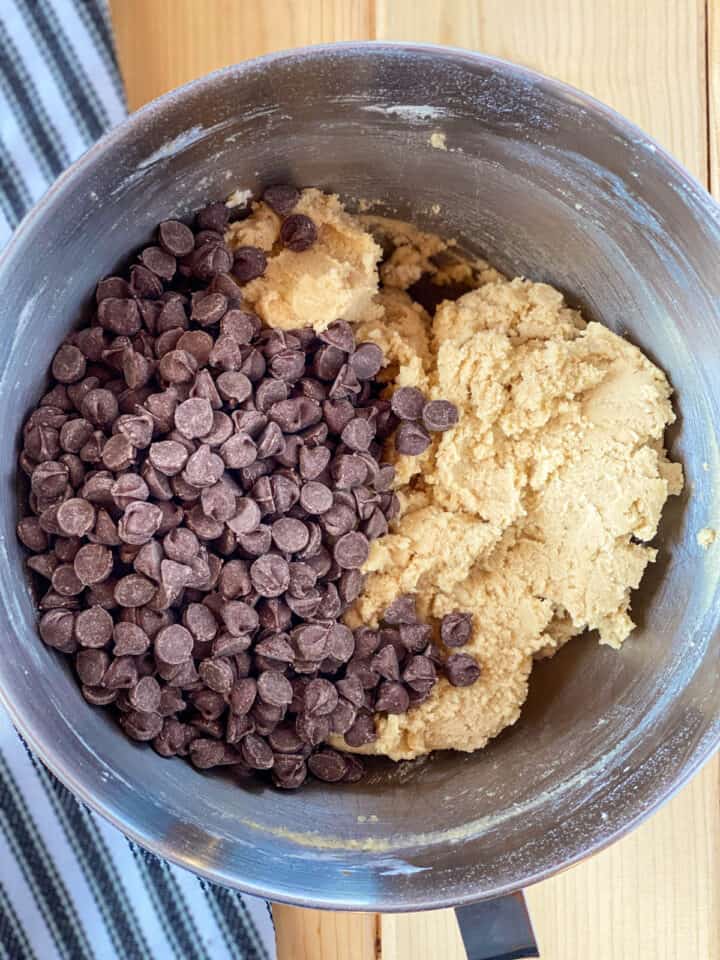 Chocolate chips added to cookie dough in large mixing bowl.