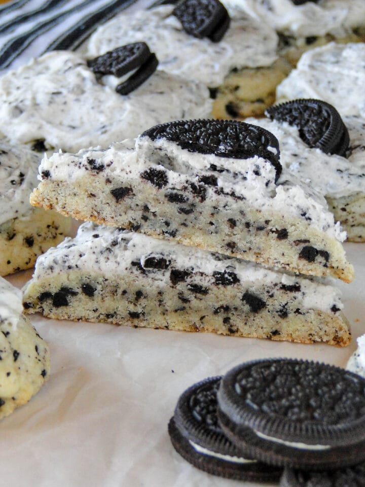 Frosted cookies and cream cookie cut in half and halves stacked showing center of cookie.