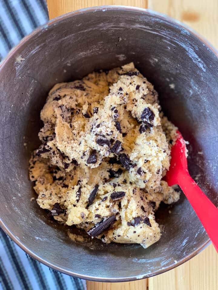 Completed cookie dough mixed in large mixing with red spatula.