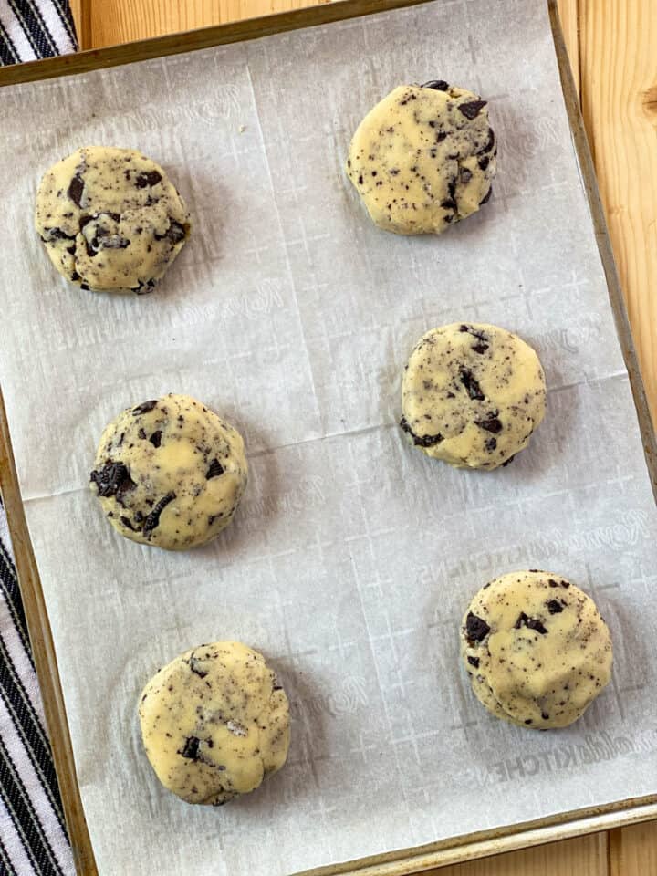 Cookie dough pucks on parchment lined cookie sheet.