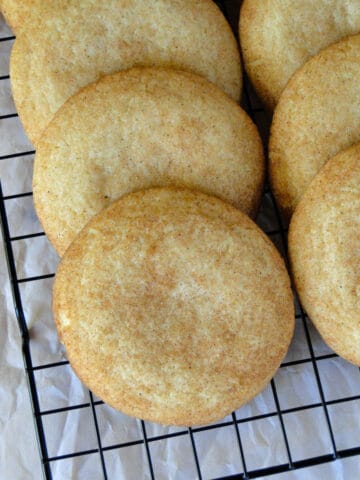 Close up view of gourmet snickerdoodle cookies layered on wire rack.