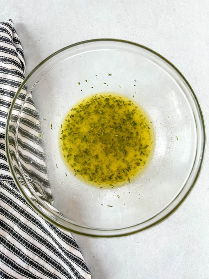 Olive oil, lemon juice, thyme, and salt mixed together in large glass bowl.