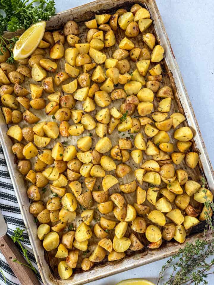 Lemon thyme roasted potatoes on sheet pan with serving spatula on the side.