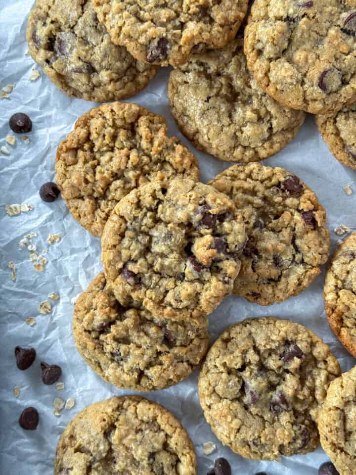 Oatmeal chocolate chip cookies in rows with cookies piled o top.