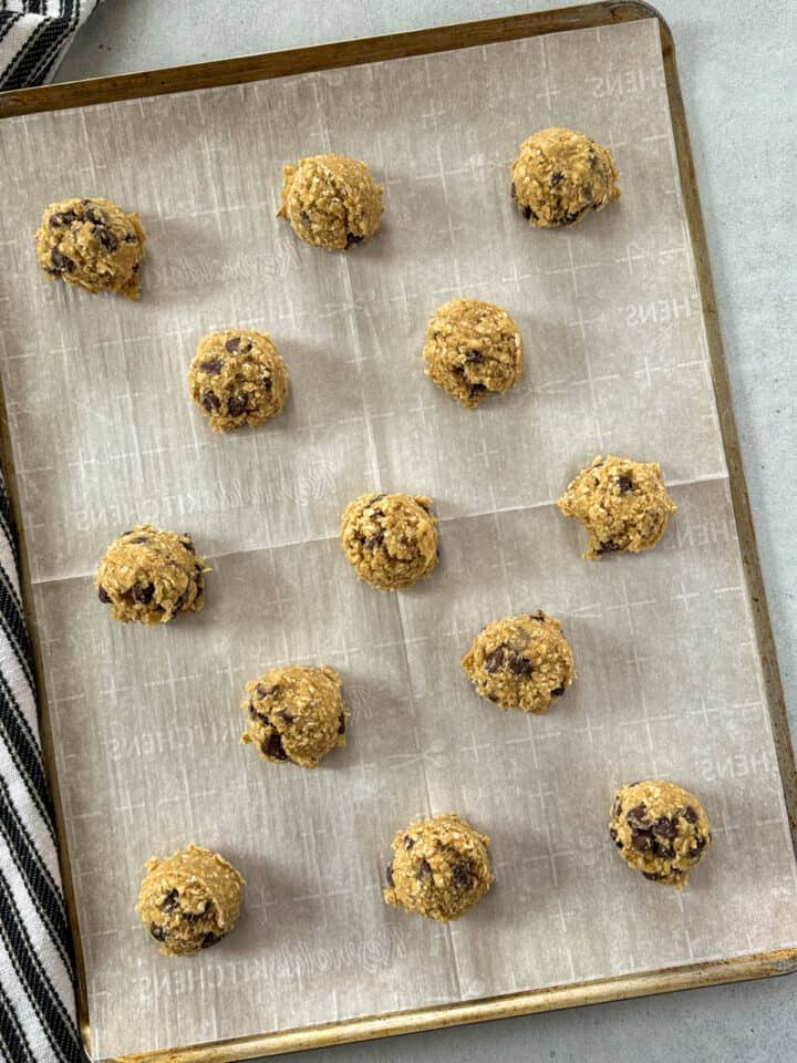 Cookie dough scoops on parchment lined cookie sheet.