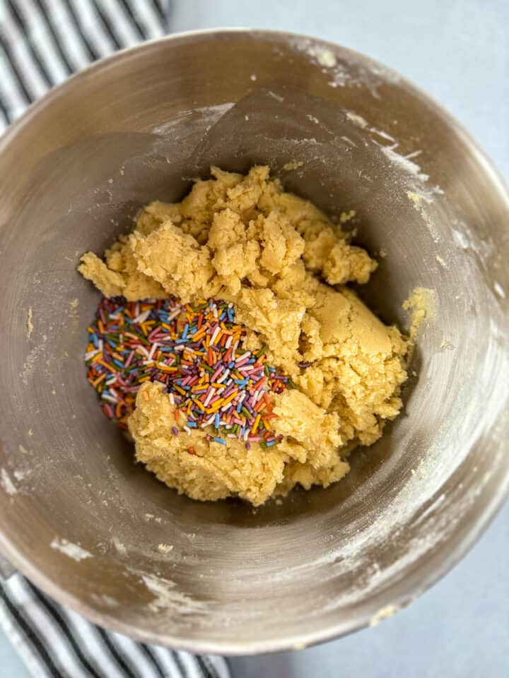 Sprinkles added to mixed cookie dough in large mixing bowl.