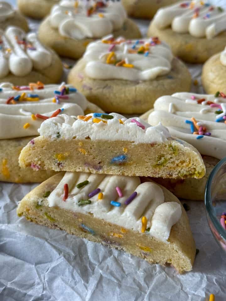 Birthday cake cookies, one cookie cut in half stacked on top of the other one showing off center of cookie.