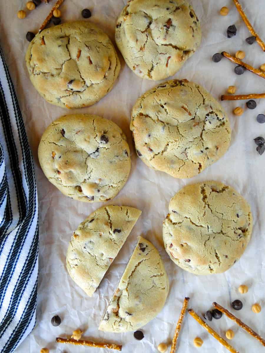 Caramel pretzel chocolate chip cookies in two columns with one cookie cut in half.