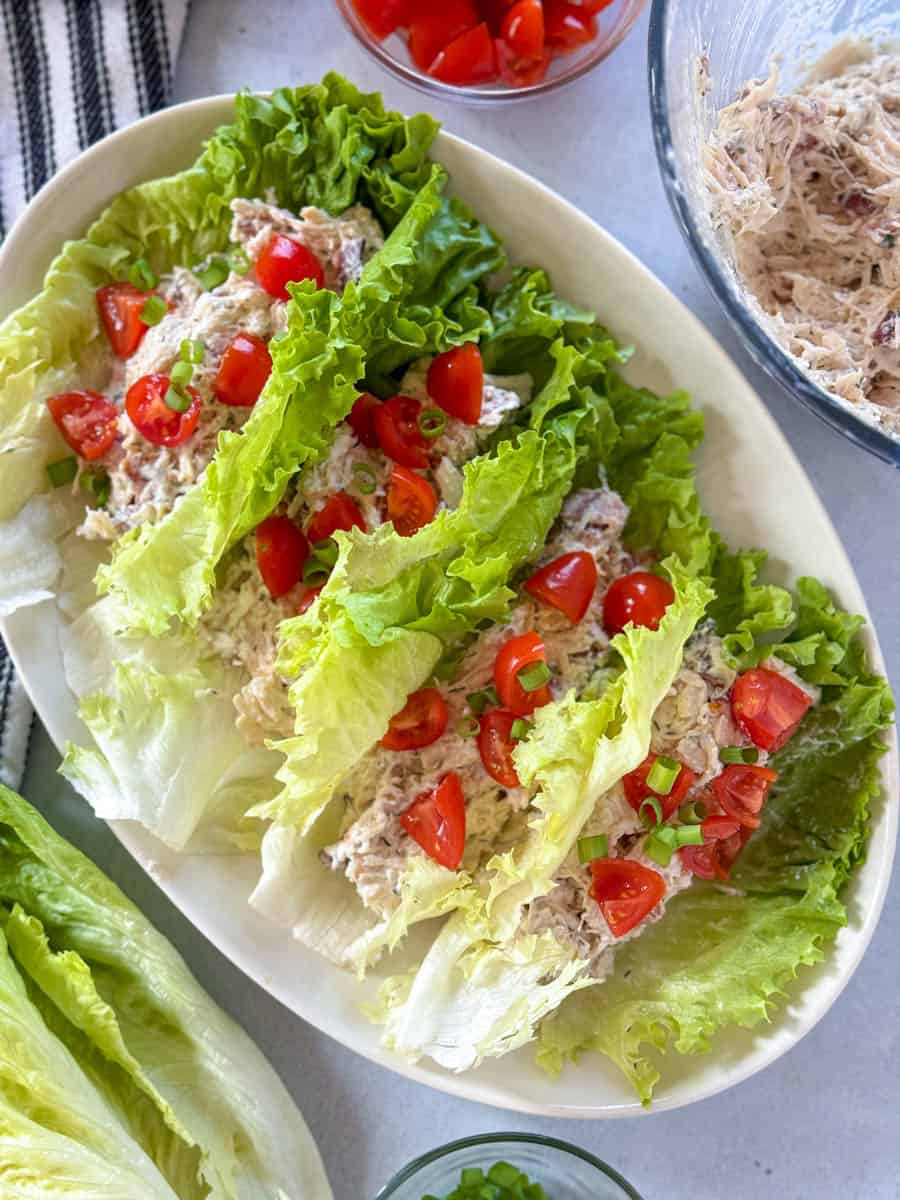 Top view of blt chicken lettuce wraps on white oval platter.