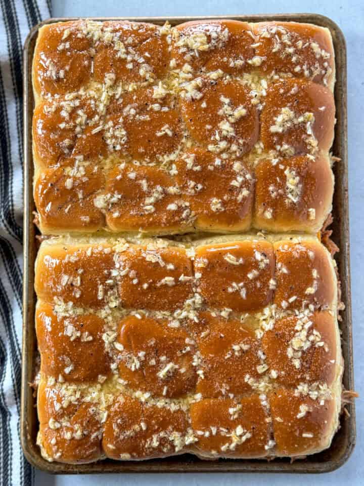 Garlic butter sauce spread over the top of the sliders.
