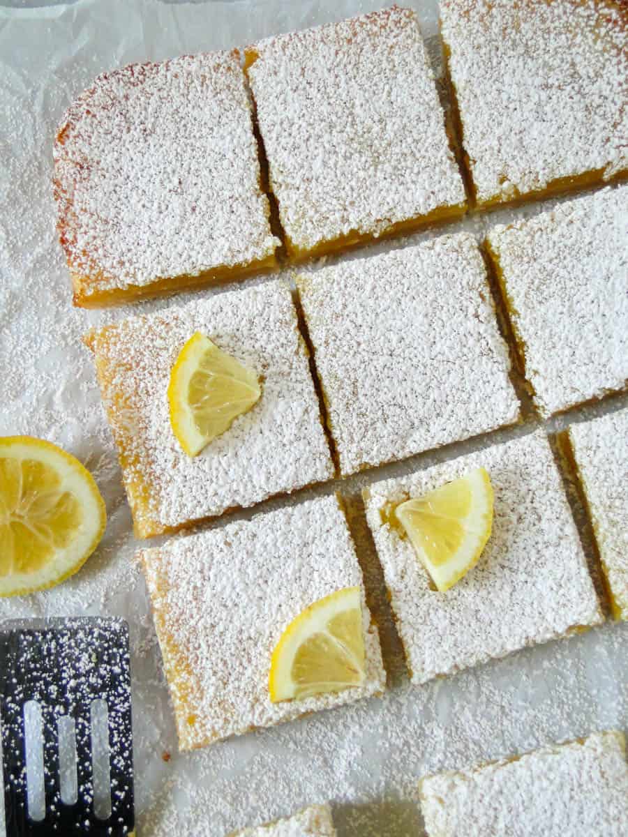 Top view of lemon bars with lemon wedge garnishes.