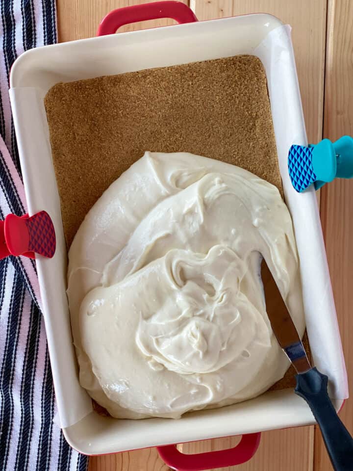 Cheesecake filling added to crust in parchment lined baking dish.