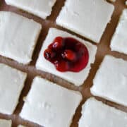 Top view of no bake cheesecake bars in rows with center bar topped with cherry pie filling.