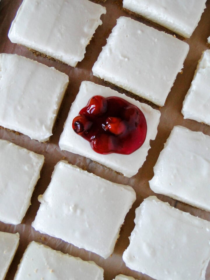 Top view of no bake cheesecake bars in rows with center bar topped with cherry pie filling.