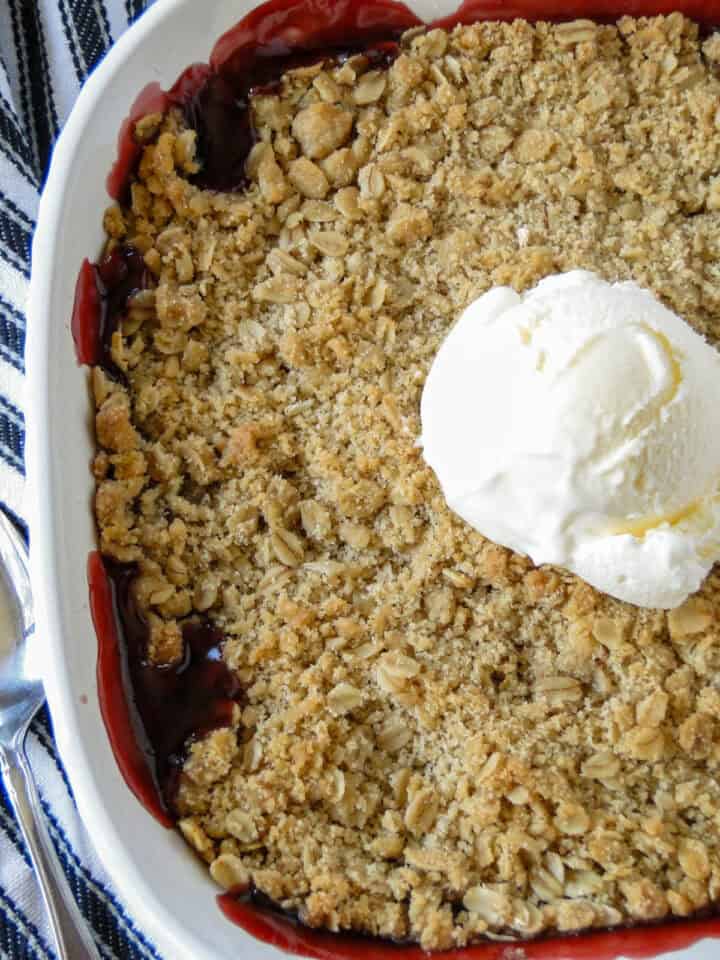 Close up top view of cherry crisp with scoop of vanilla ice cream.