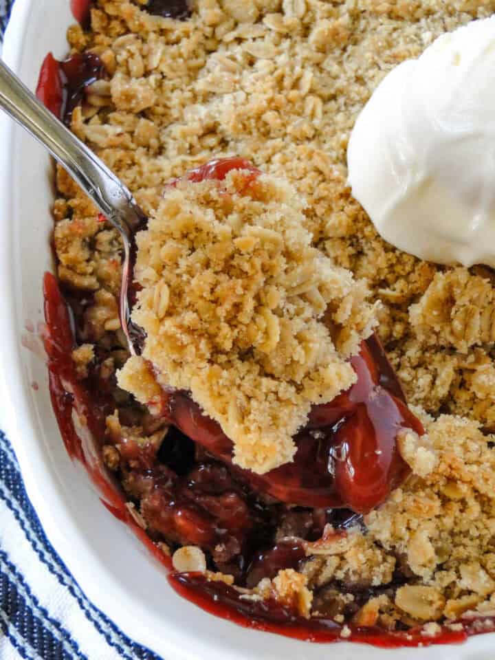 Cherry crisp being scooped out of baking dish.
