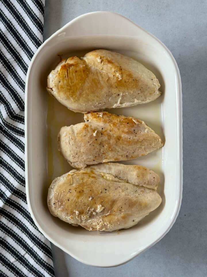 Seared chicken in white rectangle baking dish.