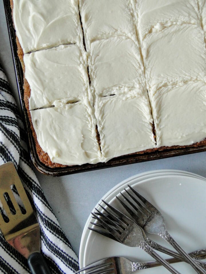 Zucchini bars sliced in pan with stack of plates next to pan.