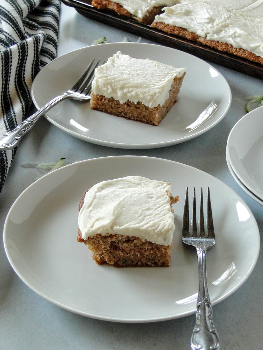 Side view of two zucchini bar slices, one on each plate with a fork.