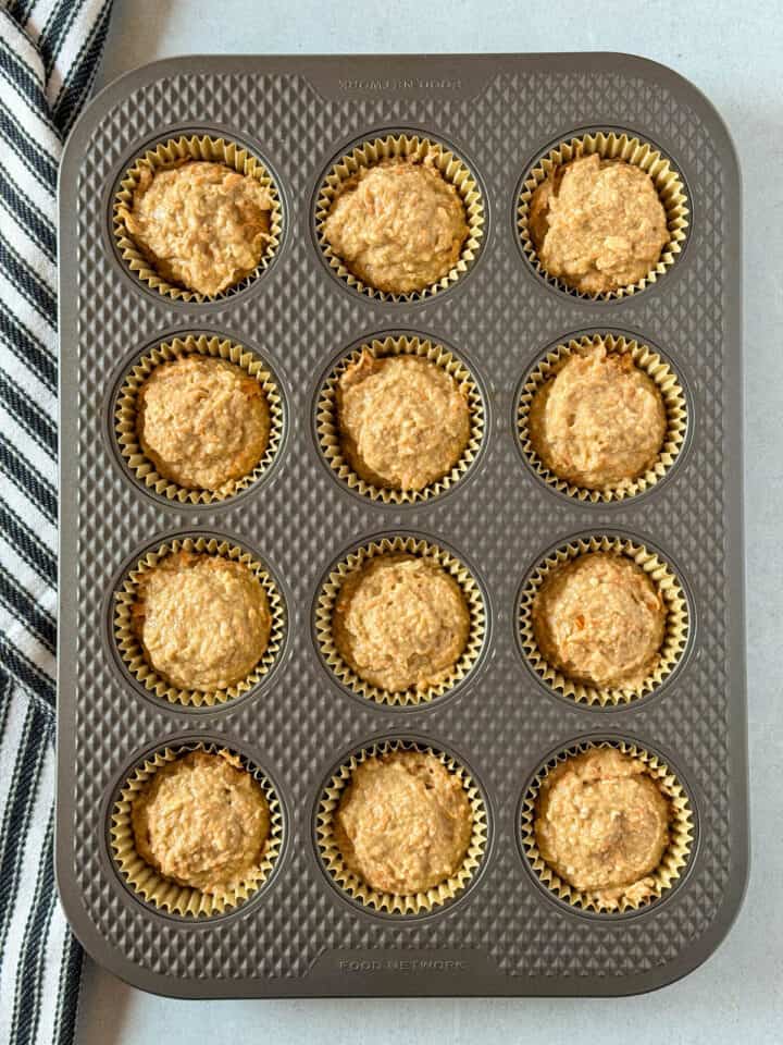 Muffin batter added to paper liners in muffin pan.