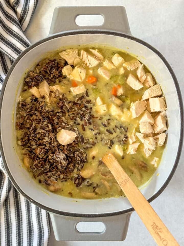 Cooked chicken and rice added to soup in dutch oven.