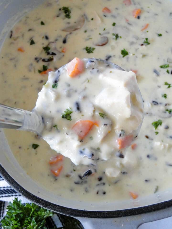 Ladleful of chicken wild rice soup out of dutch oven.