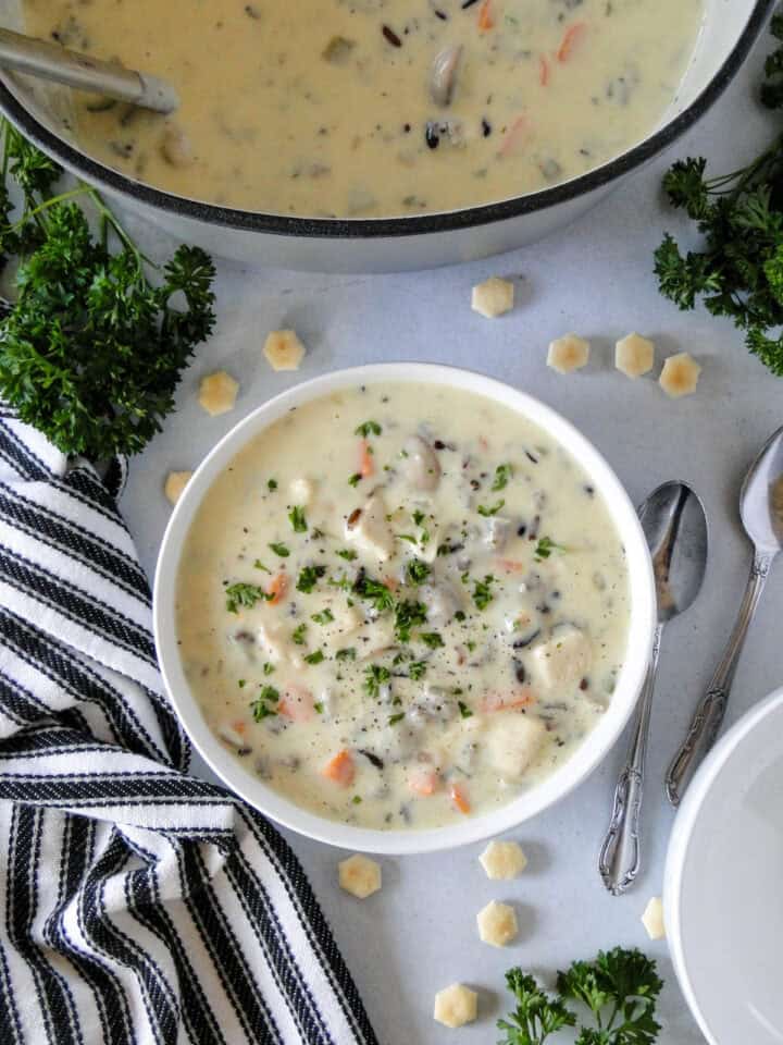 Top view of chicken wild rice soup in white bowl next to dutch oven full of soup.