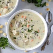 Bowl of chicken wild rice soup next to another bowl of soup with spoons on the side.