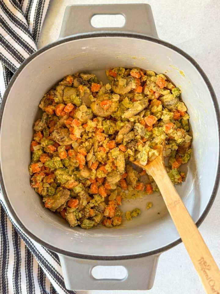 Flour stirred into veggies with wooden spoon.