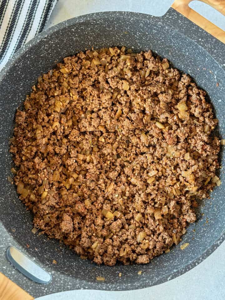 Minced garlic, tomato paste, and spices added to cooked hamburger and onions in large skillet.