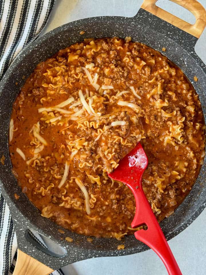 Shredded mozzarella and parmesan cheese stirred into lasagna skillet in large skillet.