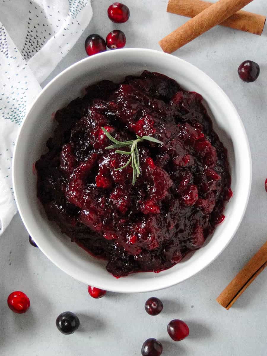 Top view of fresh cranberry sauce in white bowl with fresh cranberries as garnish on the side.