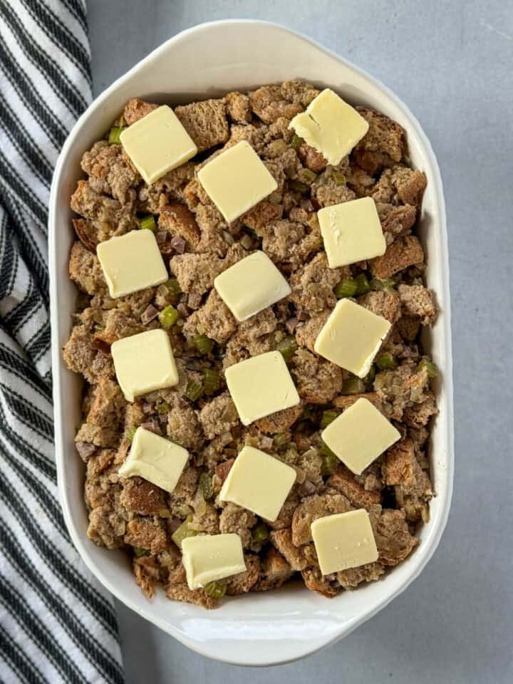 Pats of butter placed on top of stuffing mixture.