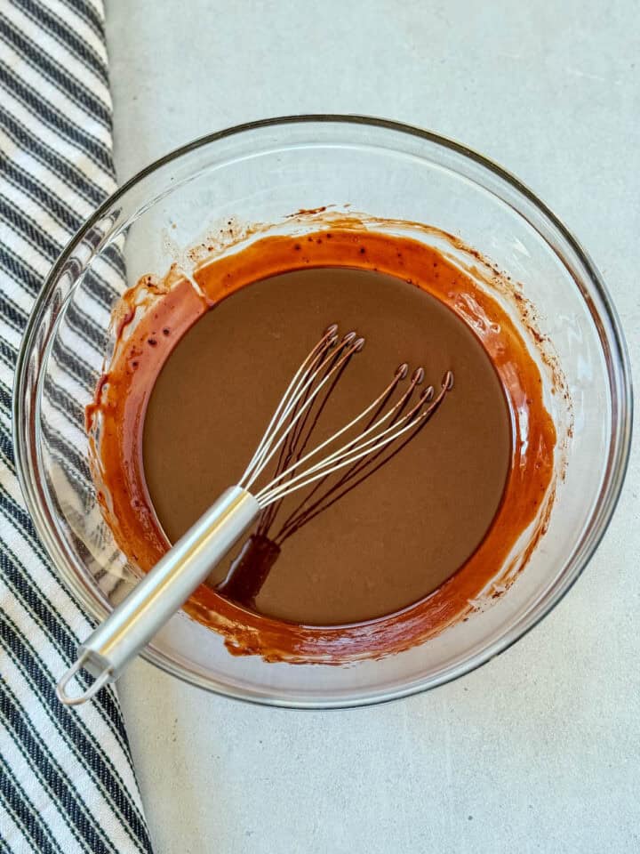Melted butter and cocoa powder whisked together with flat whisk in large glass mixing bowl.