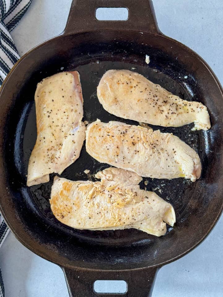 Browned chicken breast in cast iron skillet.