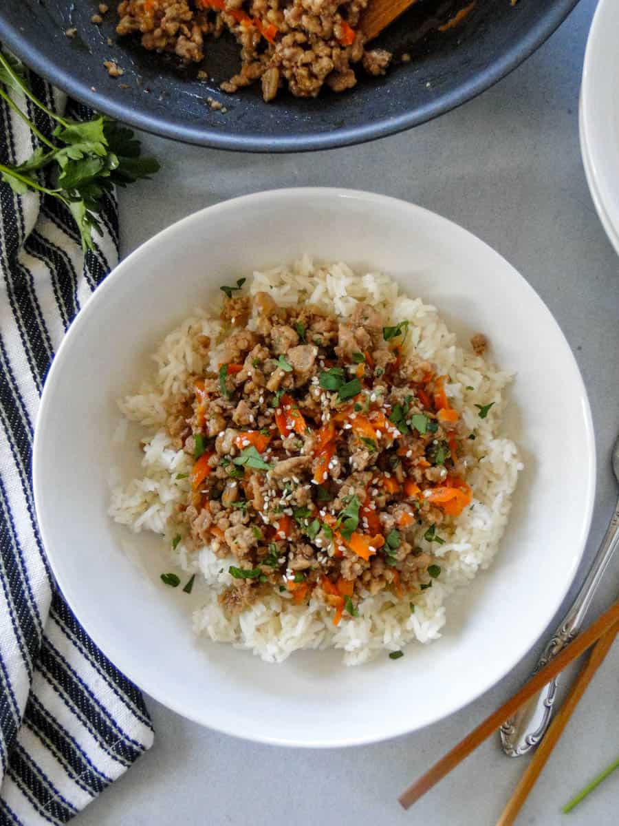 Close top view of ground turkey teriyaki over white rice in white dinner bowl.