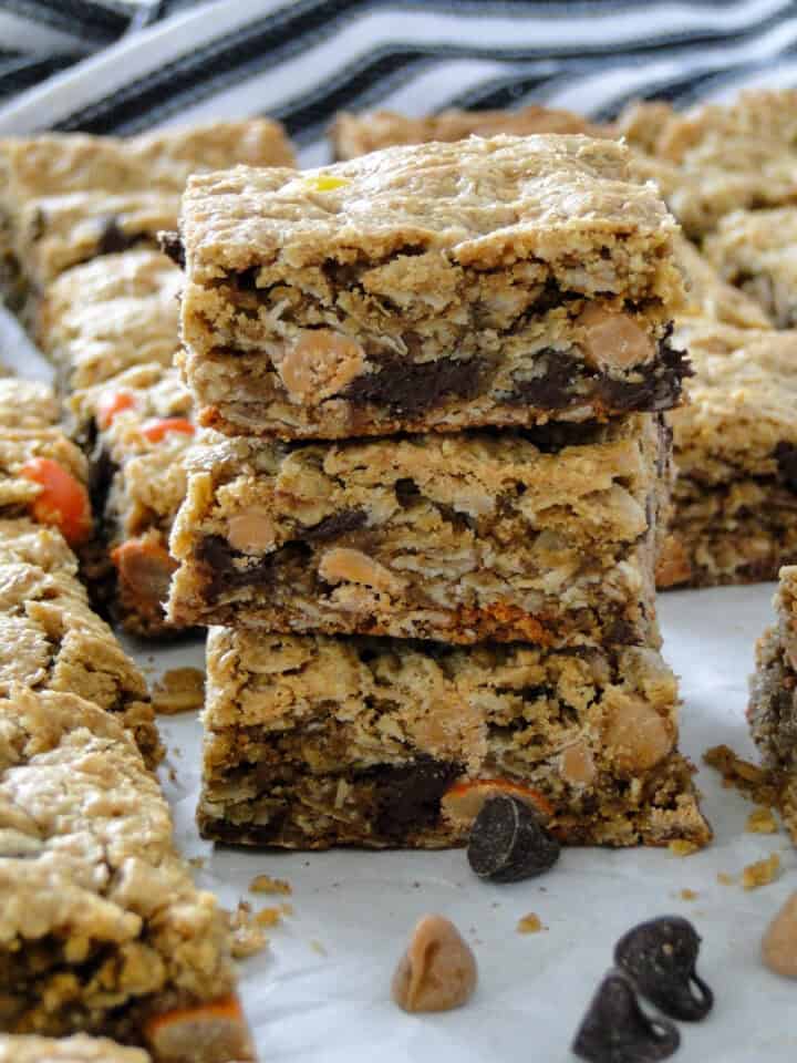 Side view of three monster cookie bars stacked in front of more bars.