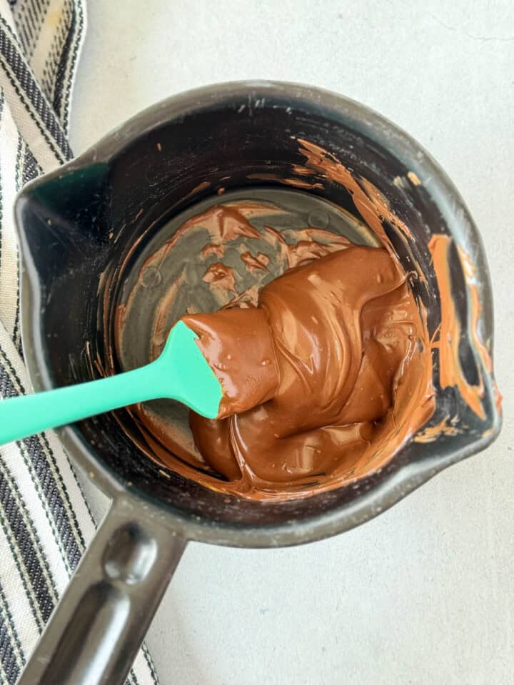 Melted chocolate and butterscotch chips stirred together with small spatula in small microwave safe bowl.