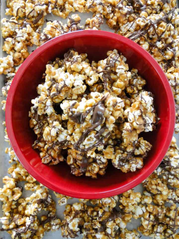 Scotcharoo popcorn in red bowl in center of more popcorn.