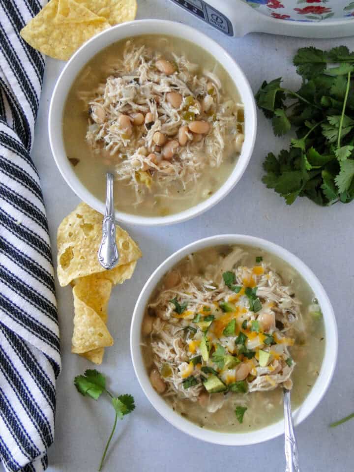Top view of two bowls of white bean chicken chili with spoons.